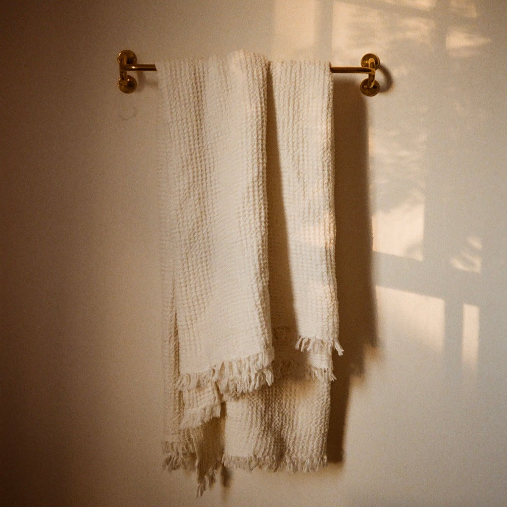Brass Maha Alavi Fauna towel bar with a hanging towel.