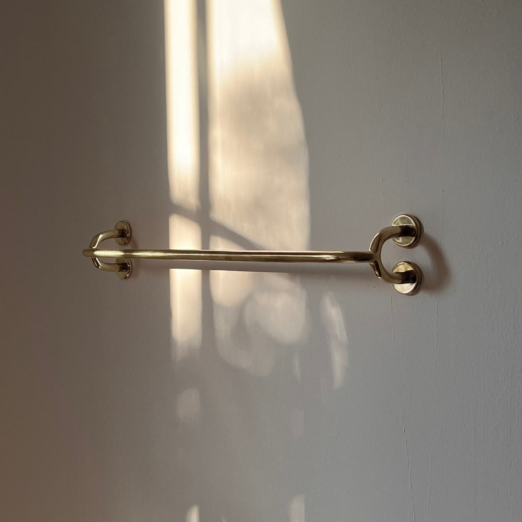 Brass Maha Alavi Fauna towel bar on a white wall.