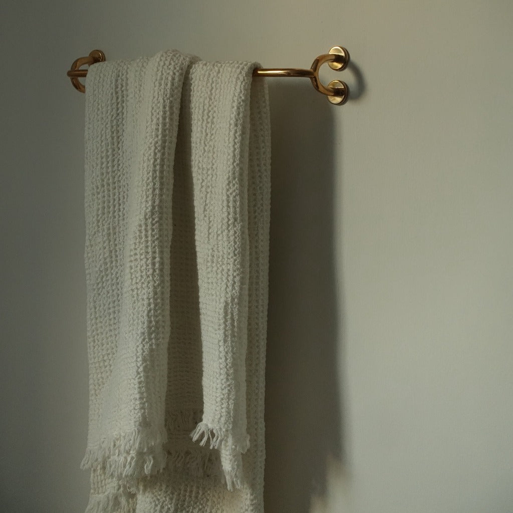 Brass Maha Alavi Fauna towel bar with a towel on a green wall.