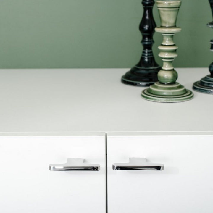 T shaped knobs in polished stainless steel mounted on a white cabinet