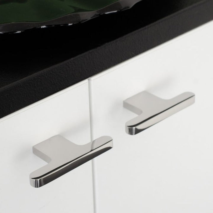 T shaped knobs in polished stainless steel mounted on a white cabinet