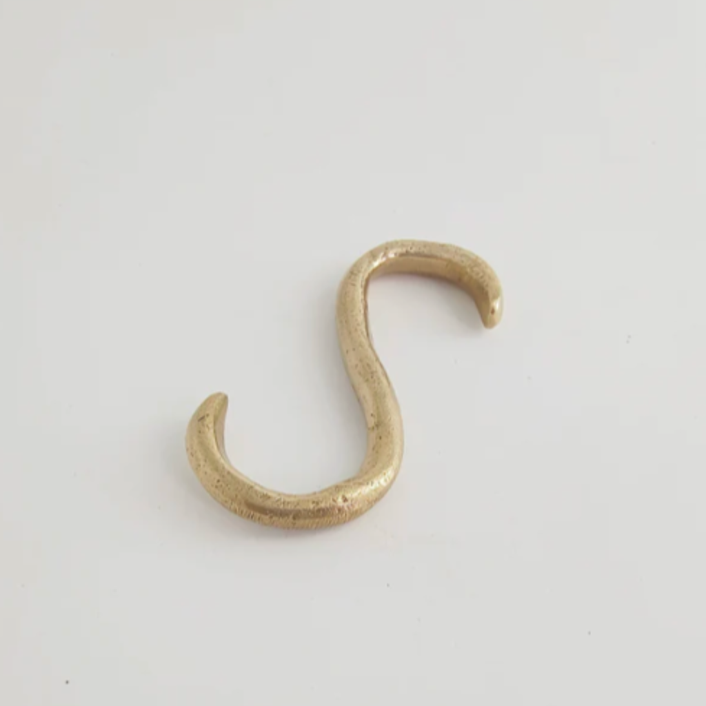 A Mi & Gei Forme No. 1 Hanging Rail hook in gold color on a white surface.