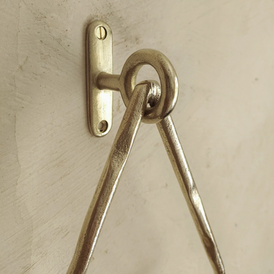 A close up of a Mi & Gei Forme No. 14 Triangle Towel Ring hanging on a wall.