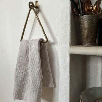 A Forme No. 14 Triangle Towel Ring by Mi & Gei hanging from a hook on a wall.
