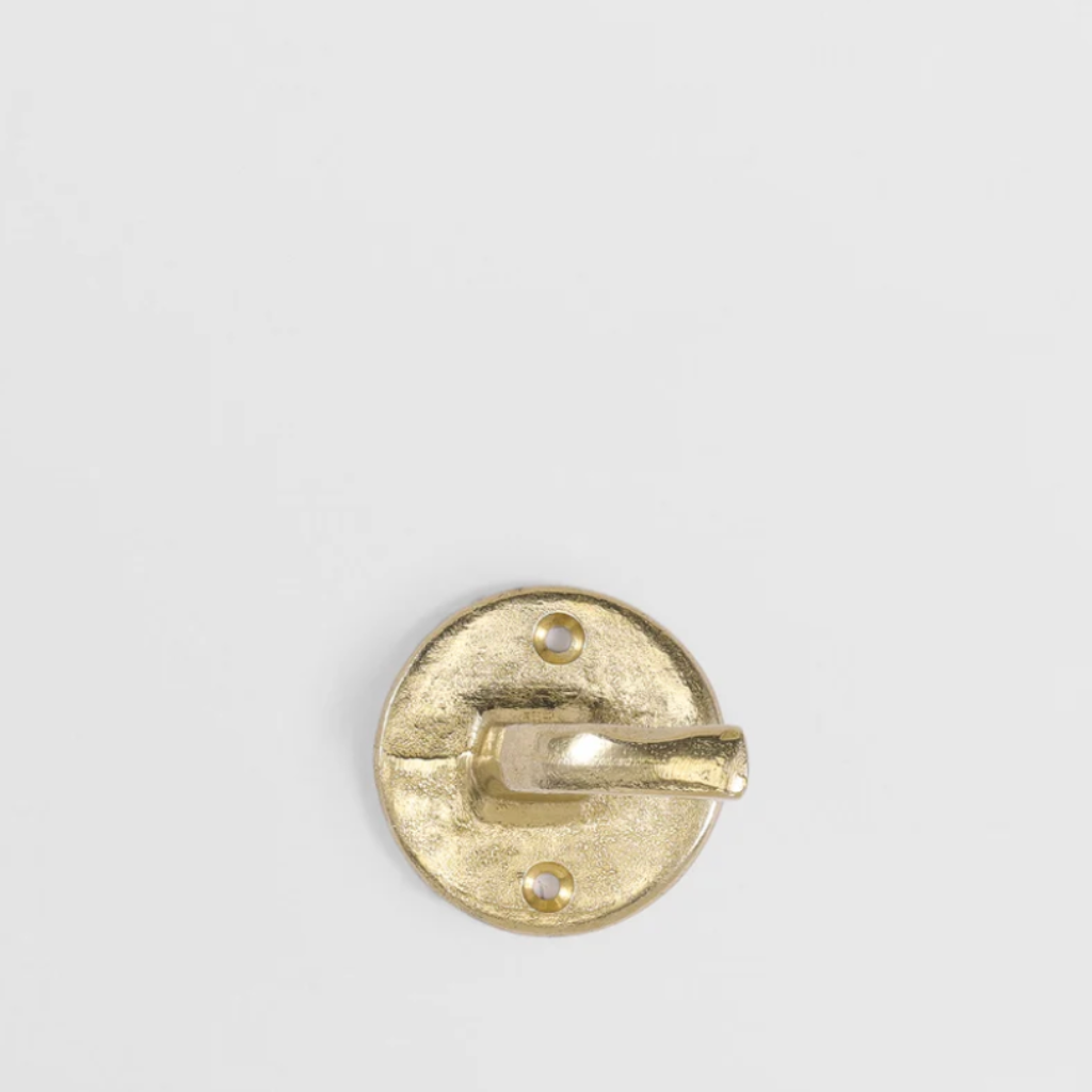 Hand-cast solid brass Forme No. 8 hook with a textured, circular base and curved profile against a white background.