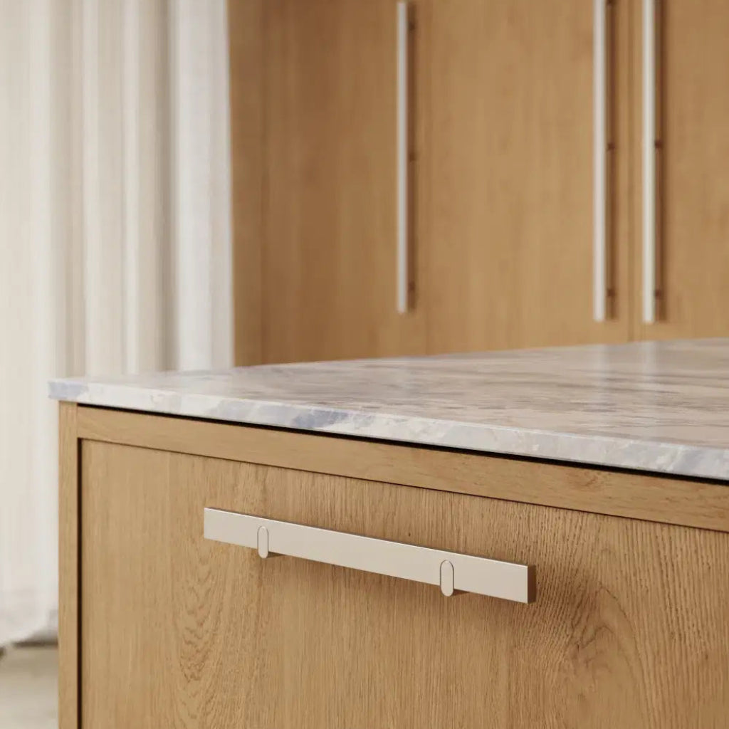 Metal cabinet pull mounted on light wood drawer