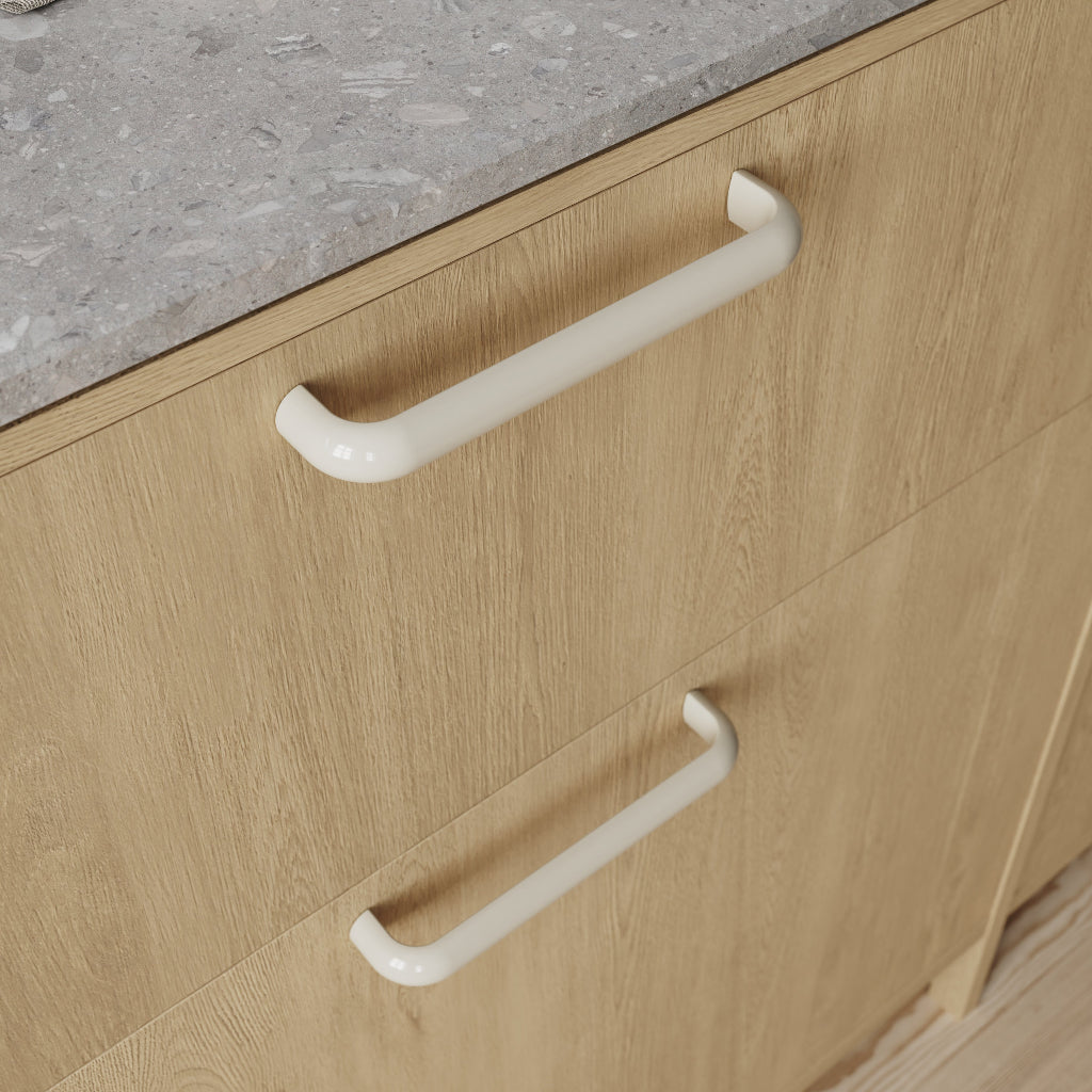 White cabinet pull mounted on light wood drawer