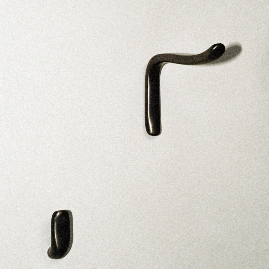 L shaped hook next to J shaped hook, mounted on wall.