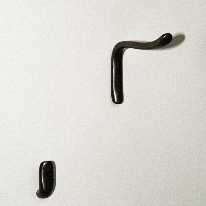 L shaped hook next to J shaped hook, mounted on wall.