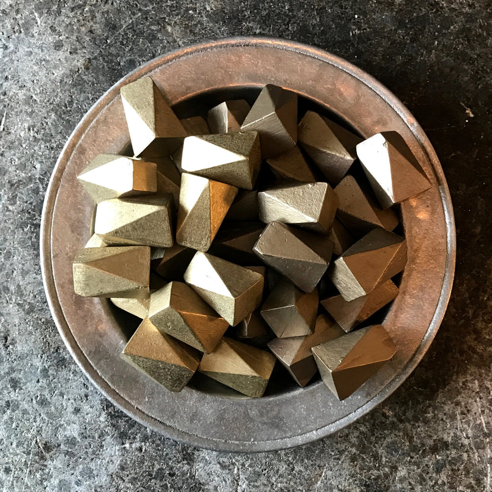 A Shayne Fox wooden bowl filled with Geo Knob / Hook silver colored cubes.