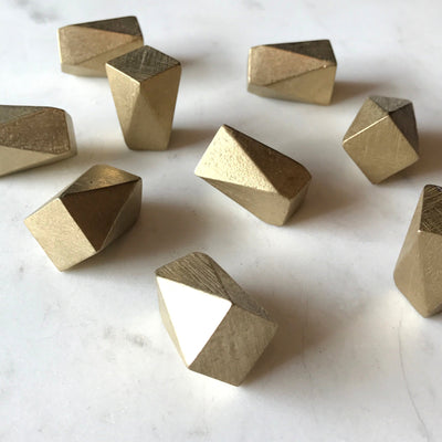 A group of Shayne Fox Geo Knobs/Hooks in gold geometric shapes on a white surface.