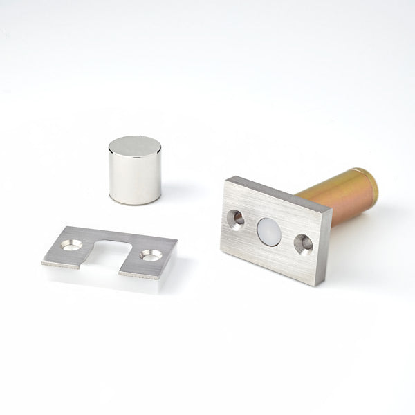A couple of Ghostop Concealed Door Stop GS200 pieces of metal sitting on top of a table.