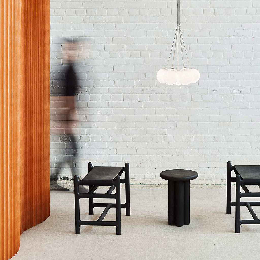 Three Anony chairs and an Anony table in front of a brick wall.