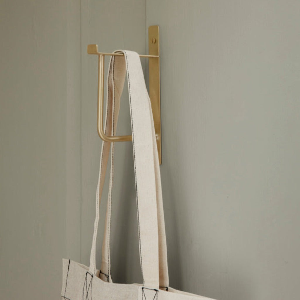 hang rack in brass on wall holding canvas bag