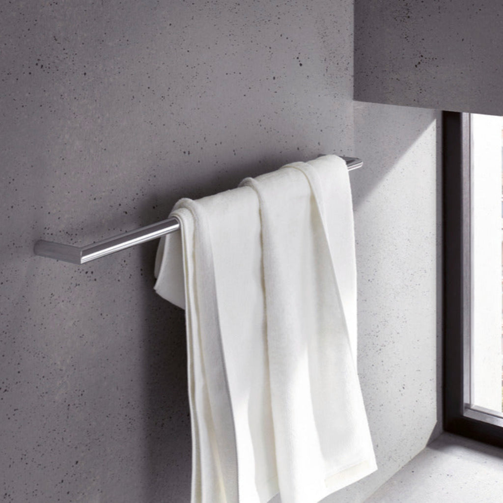 White towel hanging on a metal towel rack against a gray wall.