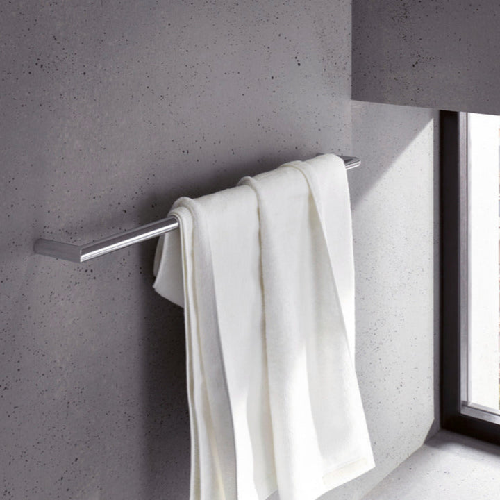 White towel hanging on a metal towel rack against a gray wall.