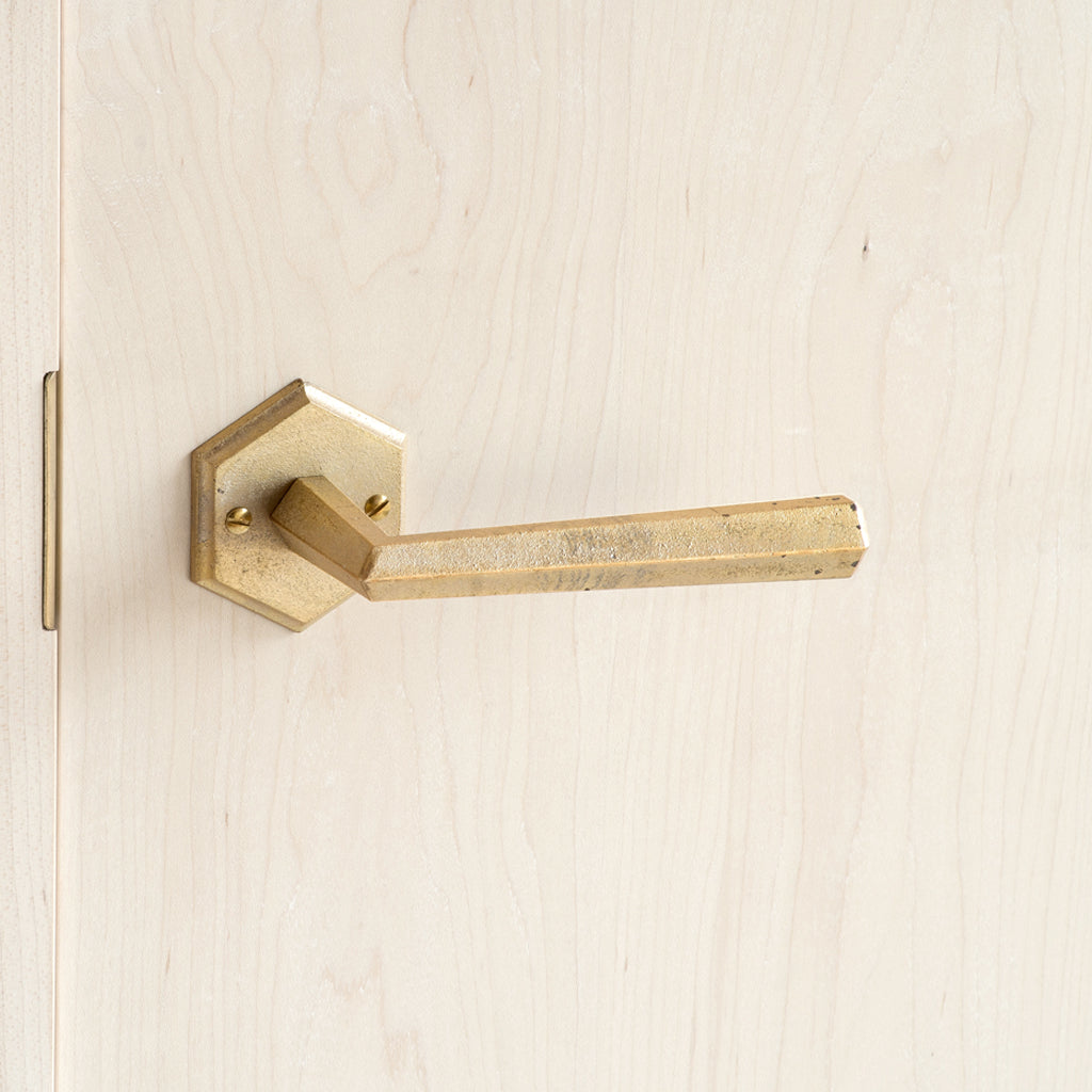A close up of a MATUREWARE Hex Lever door handle on a wooden door.