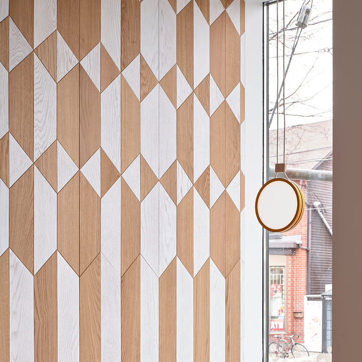 A wooden wall with a Highwire Pendant clock hanging from Anony's side.