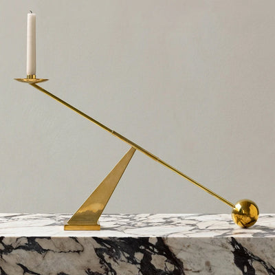 Brass Interconnect Candle Holder from Menu styled on textured marble table against grey wall.