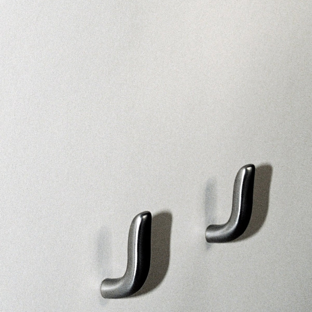 Two softly curved J shaped hooks in satin nickel, mounted to wall.