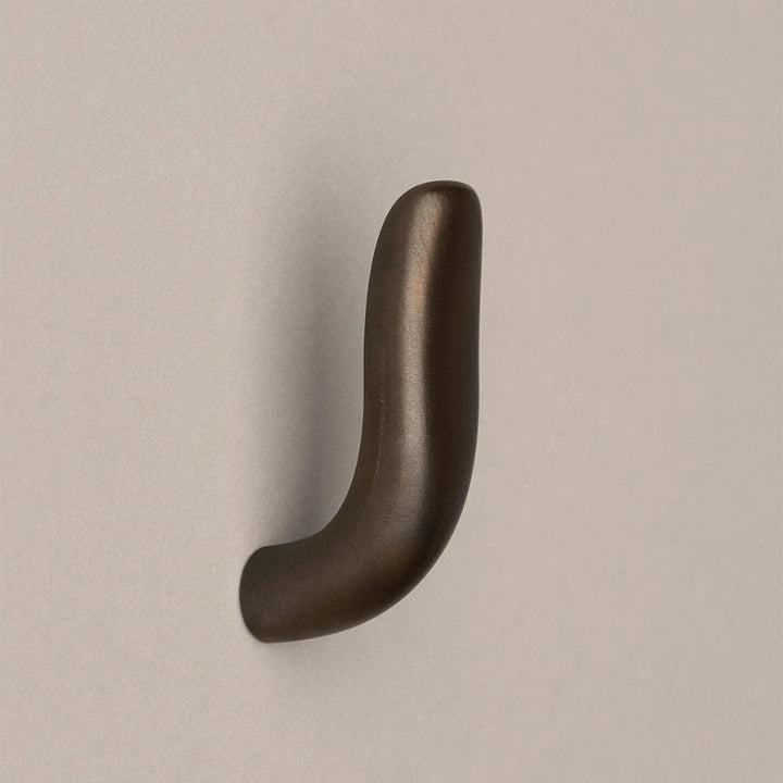 Softly curved J shaped hook in dark brass, side view.