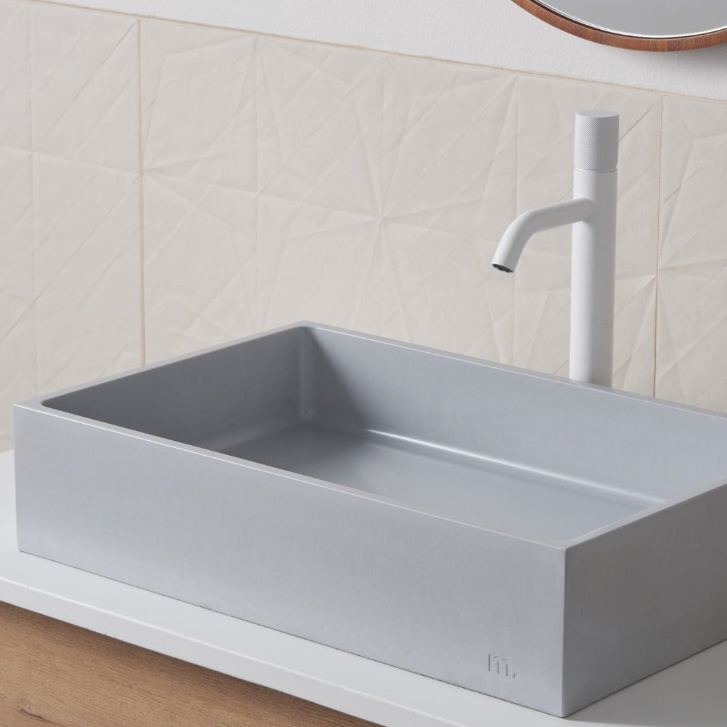 A mudd. concrete Jeker Basin sitting on top of a wooden counter.