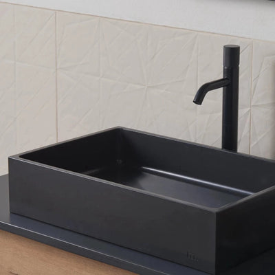 A mudd. concrete Jeker Basin sink sitting on top of a wooden counter.