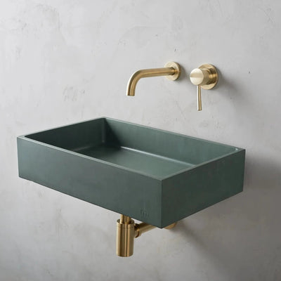 A mudd. concrete Jeker Basin Affix with a gold faucet and a green square sink.