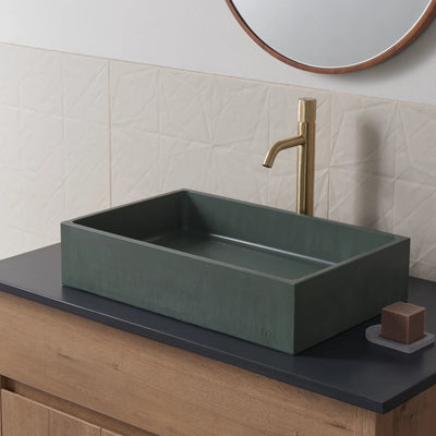 a mudd. concrete Jeker Basin sitting on top of a wooden counter.
