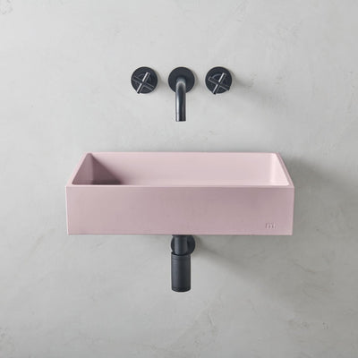 A mudd. concrete Jeker Basin Affix with a black faucet and a pink sink.