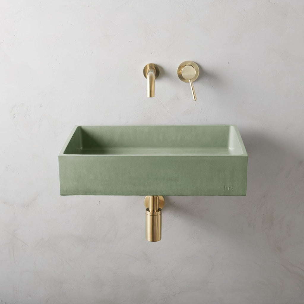 A mudd. concrete Jeker Basin Affix with a gold faucet next to it.
