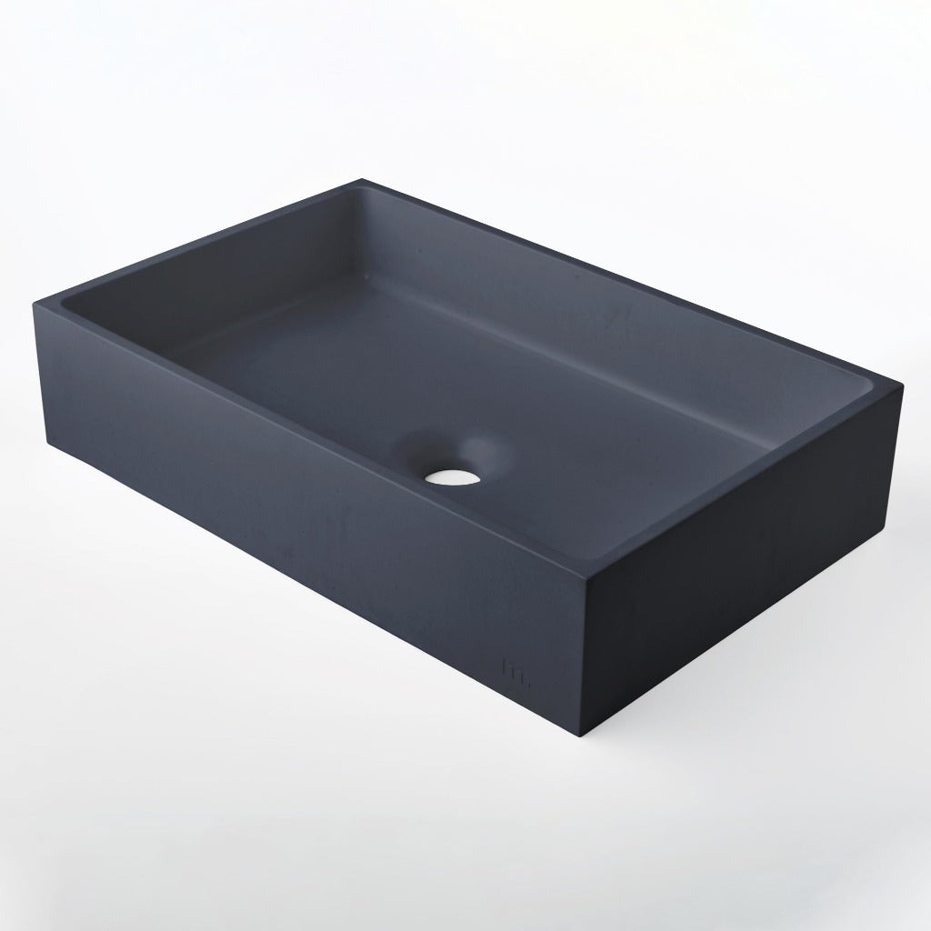 A black Jeker Basin sink with a hole in the middle of it by mudd. concrete.