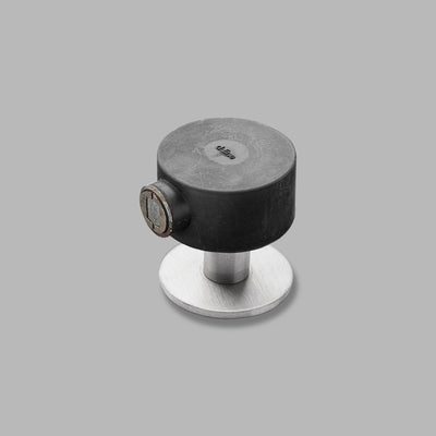 A d line black and silver Knud Floor Door Stop Tall knob on a gray background.