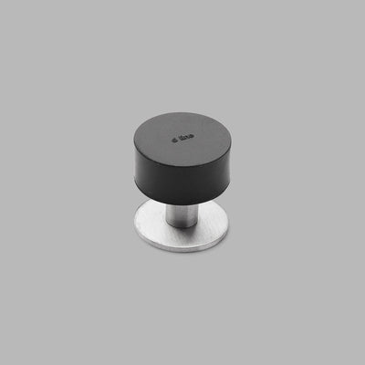 A d line black Knud Floor Door Stop Tall with a metal base on a gray background.
