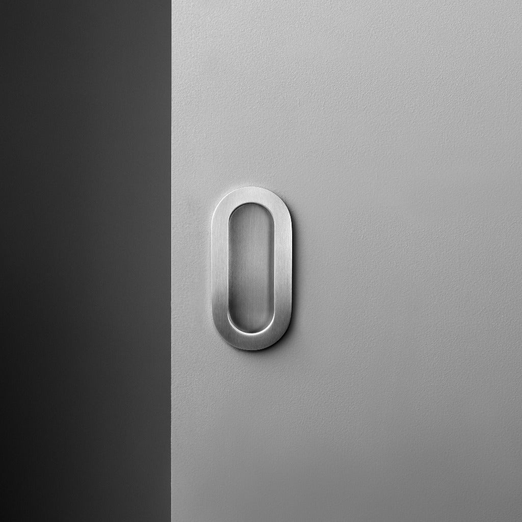 A white door with a d line Knud Oval Flush Pull on it.