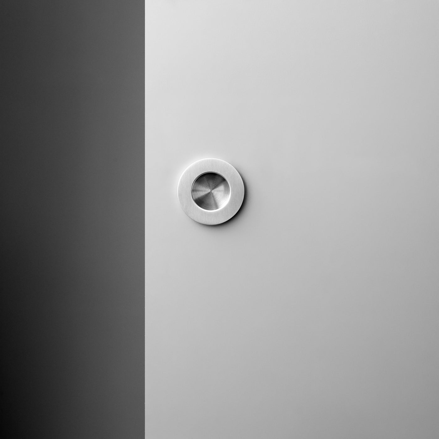 A white door with a Knud Round Flush Pull by d line on it.