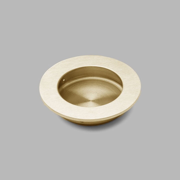 A dline Knud round flush pull in satin brass.