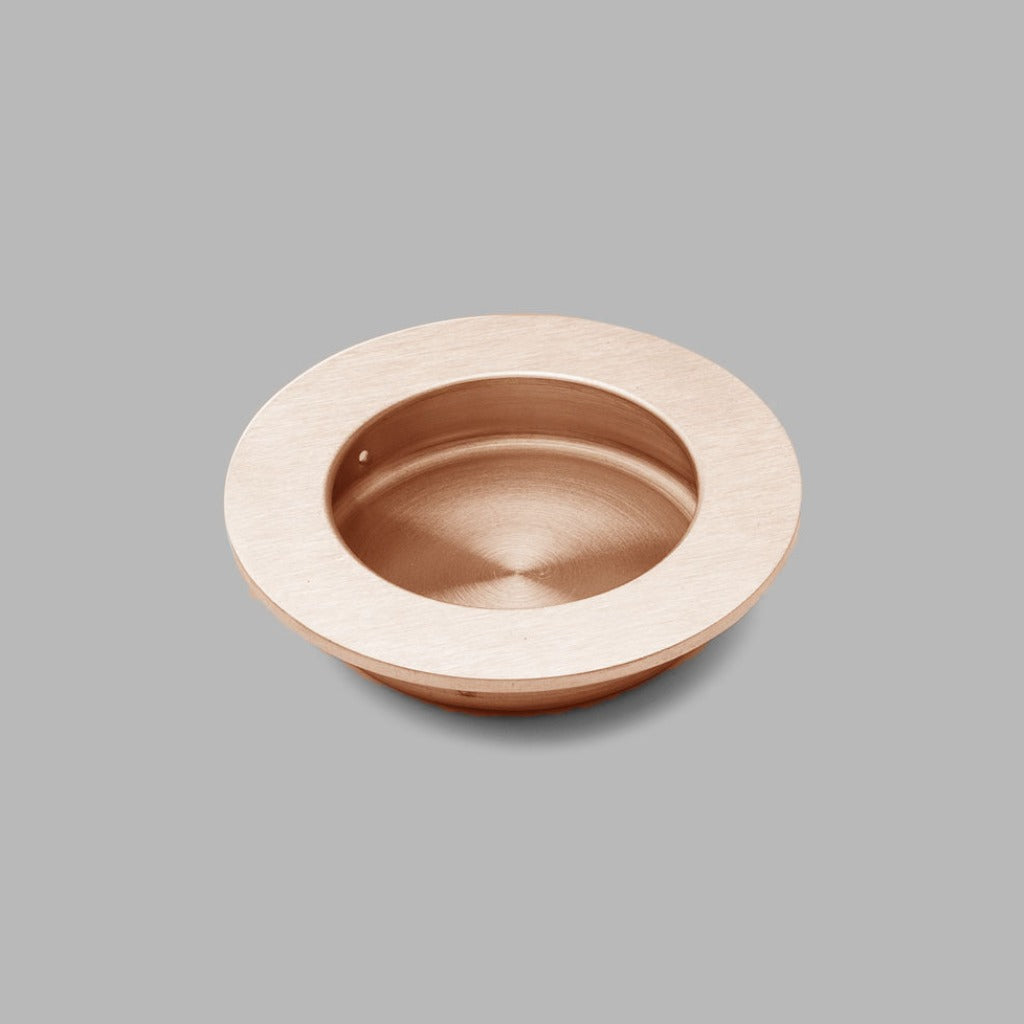 A dline Knud round flush pull in copper.