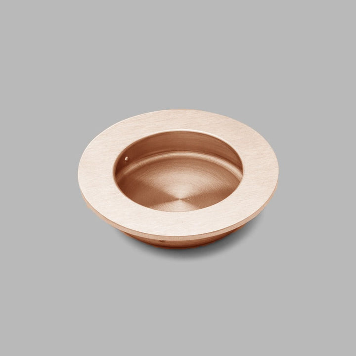 A dline Knud round flush pull in copper.