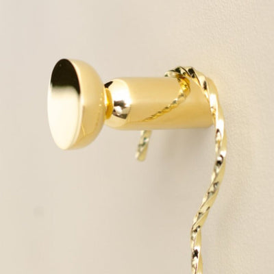 Round hook in polished brass mounted on wall