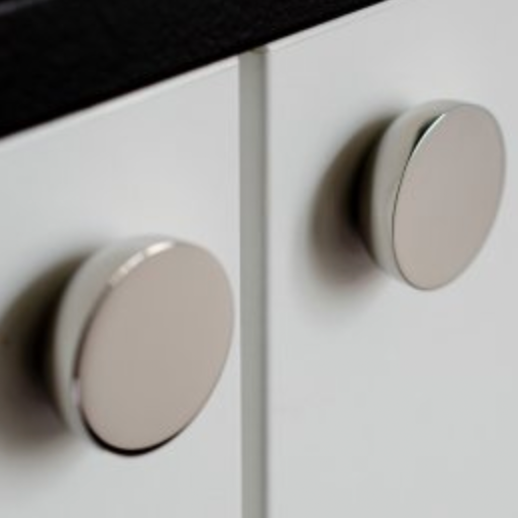 Round knob in polished stainless steel by Baccman Berglund mounted on white cabinet