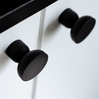 Round knob / hook in black aluminum mounted on white cabinet