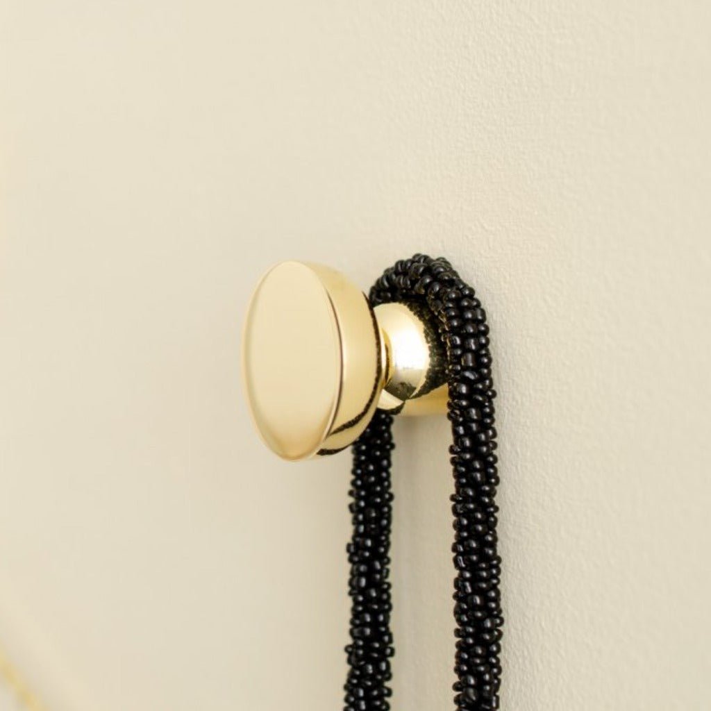 Round knob / hook in polished brass mounted on wall