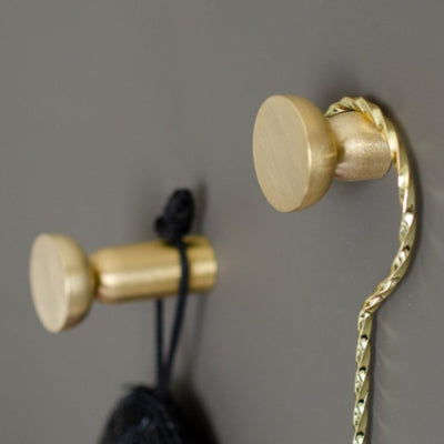 Round knob / hook in brushed brass mounted on wall