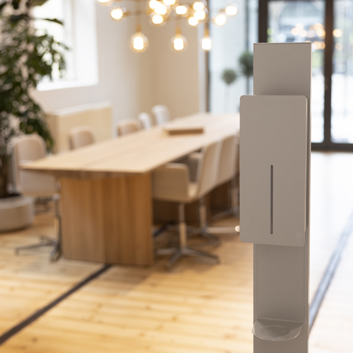 White Hand Sanitizer on stand located in boardroom environment.