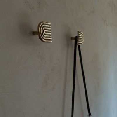 A couple of Mi & Gei Libre Forme No. 9 Hooks on a wall near a wall.