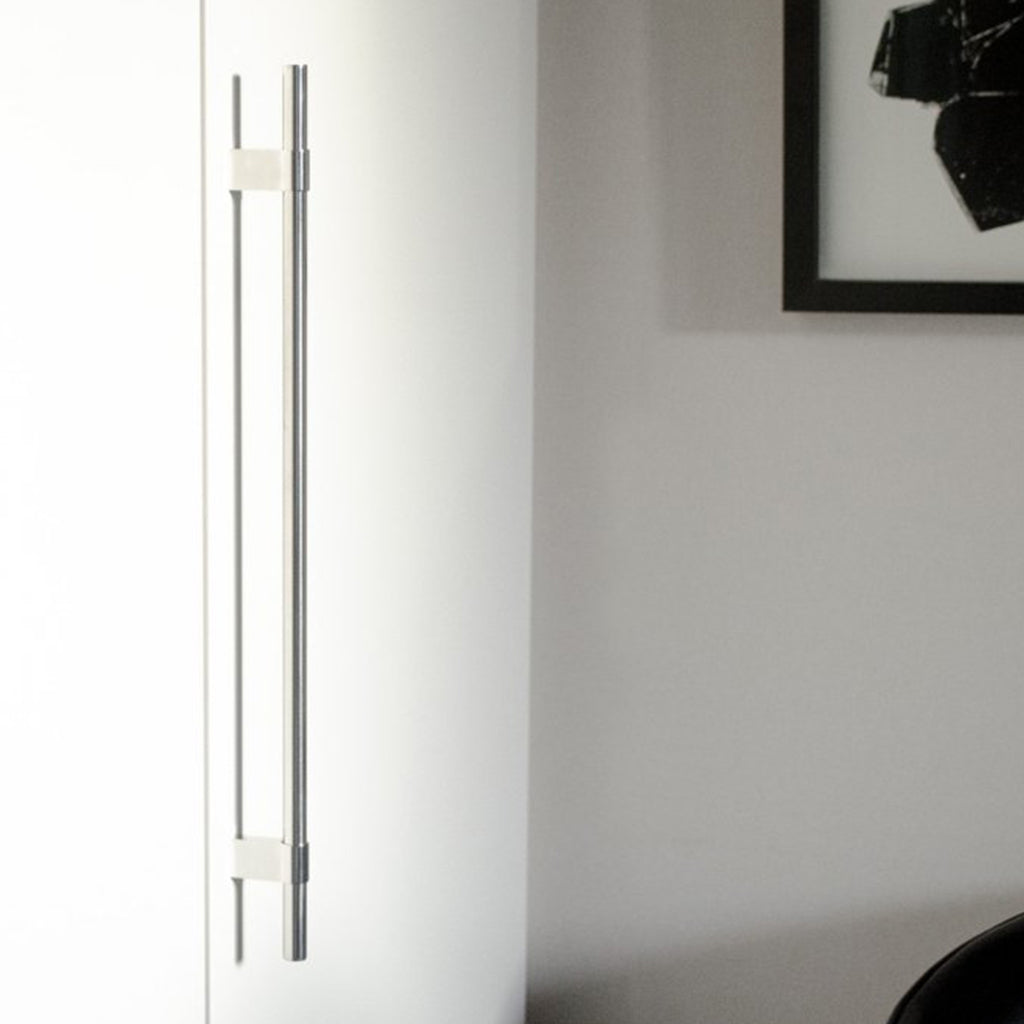 A white Baccman Berglund Line Big Handle refrigerator freezer sitting next to a black chair.