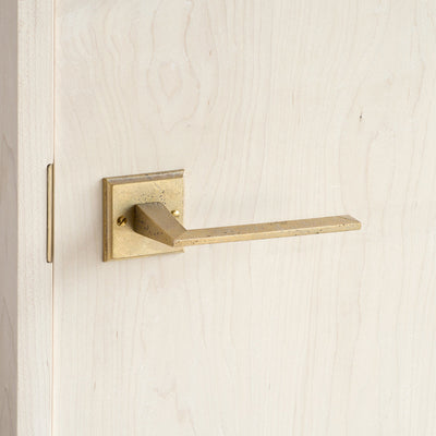 A close up of a MATUREWARE Line Lever door handle on a wooden door.