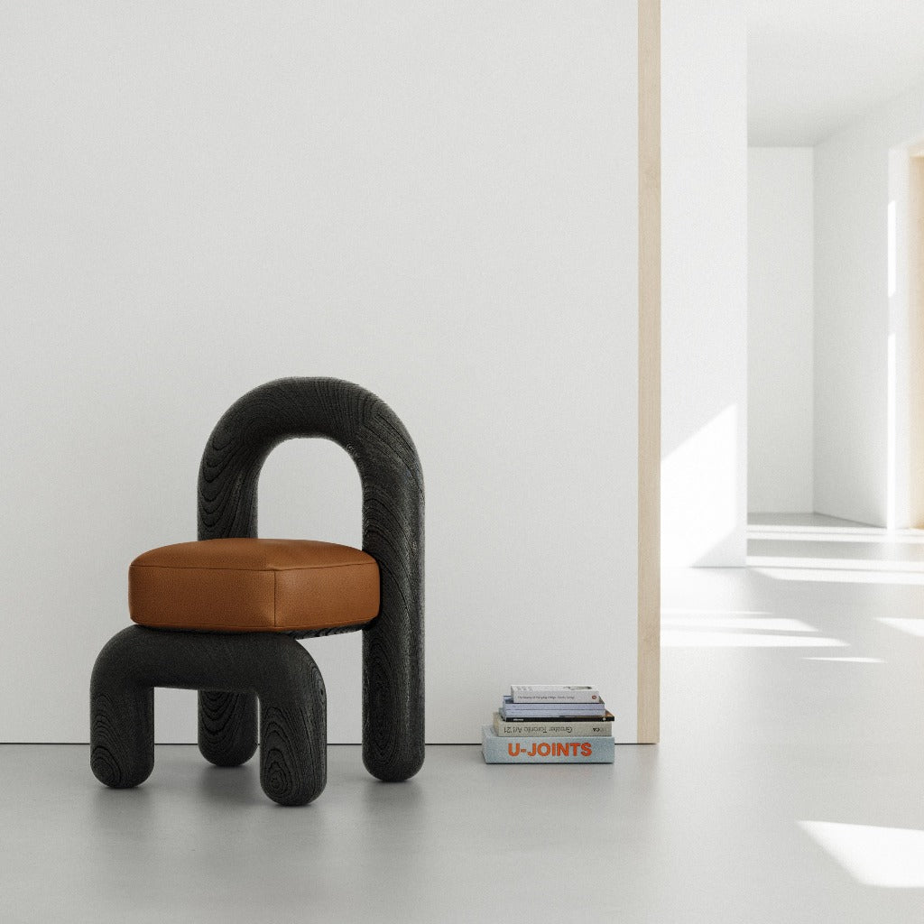 lithic dining chair in white room with black oak frame and cognac leather seat