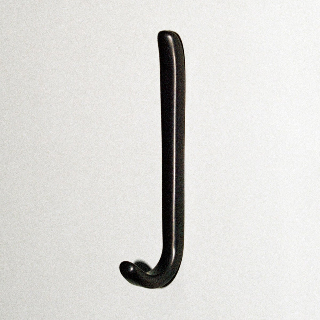 Long J shaped hook in dark brass, mounted to wall.